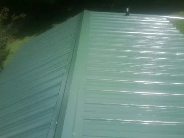 New green metal panels meeting at the ridge of a roof — Flat Roof Repair work by our crew in Hampton