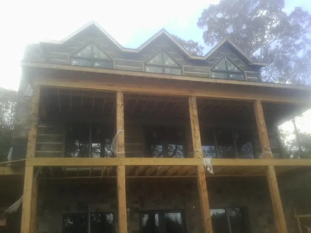 Dormers and porch framing on a large log home under construction — Roof Coating work by our crew in Hampton